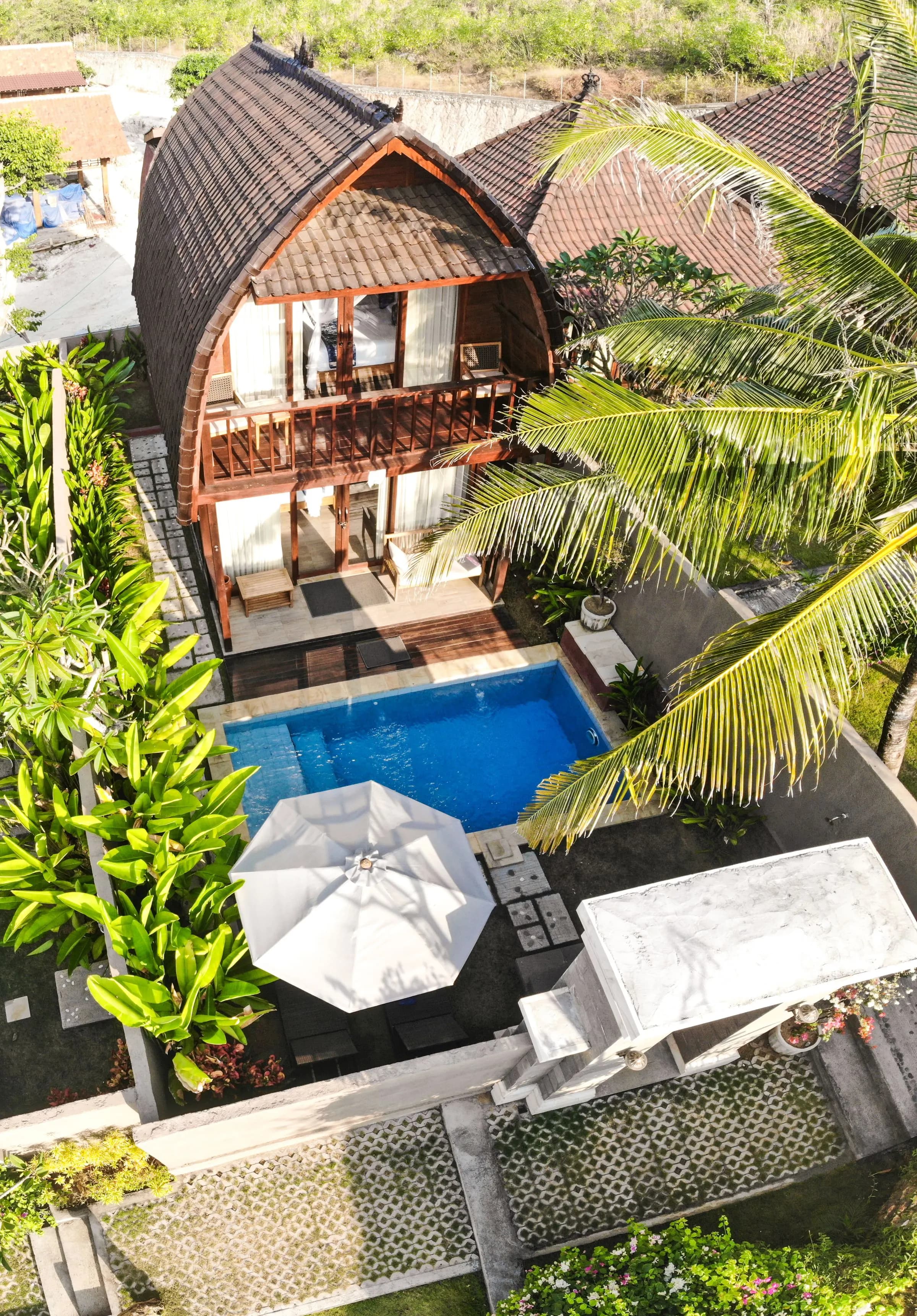 Timber villa and pool seen through palms