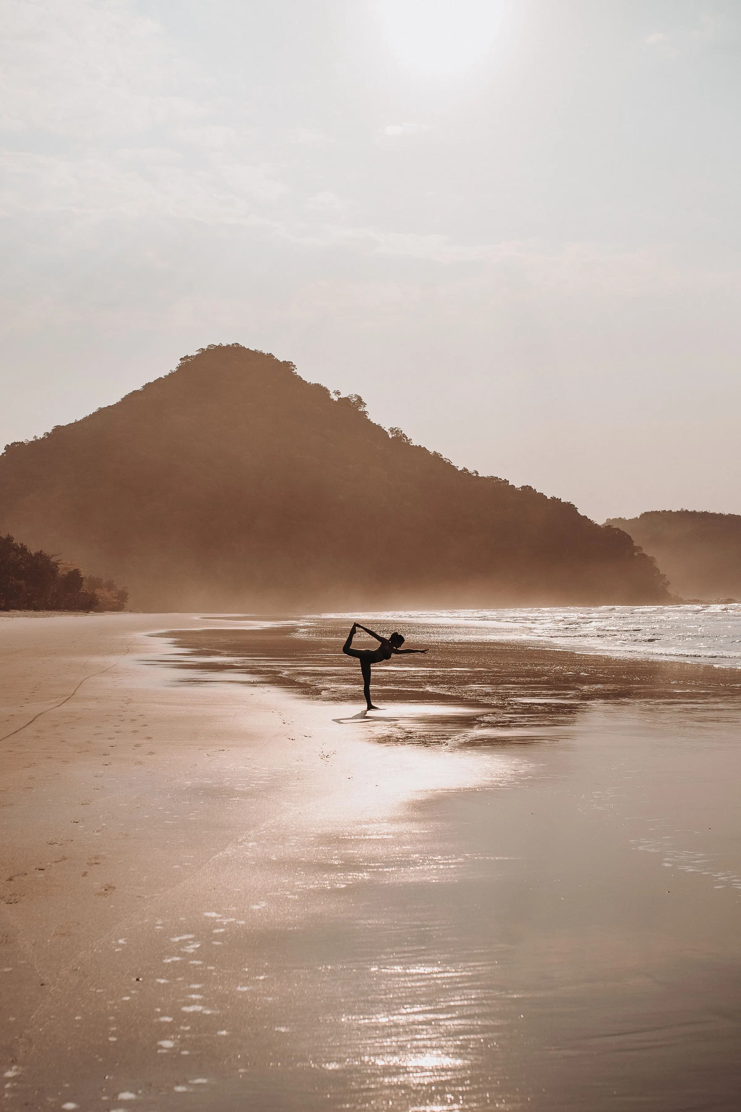 Yoga on a misty beach at dawn